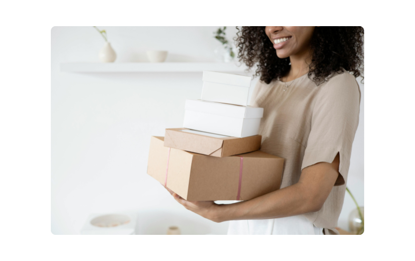 Smiling woman carrying stacked packages, showcasing side hustle ideas for starting a small online business from home.